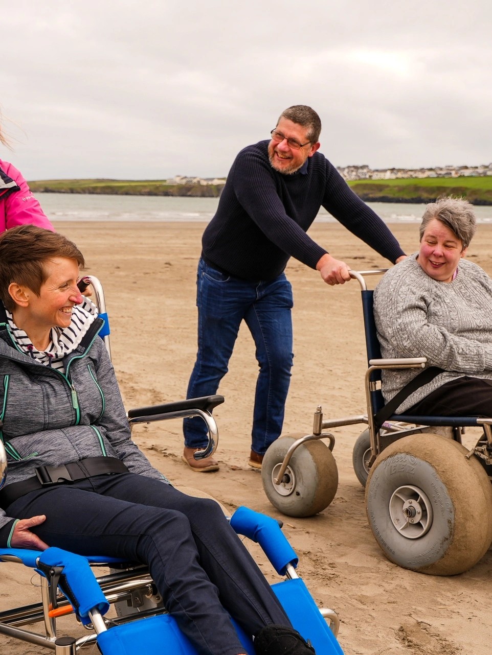 A beach walk with 'tramper' wheelechairs, with the people smiling at each other. / Taith cerdded ar draeth gyda cadeiriau olwyn 'tramper', gyda'r phobl yn gwenu ar eu gilydd. 