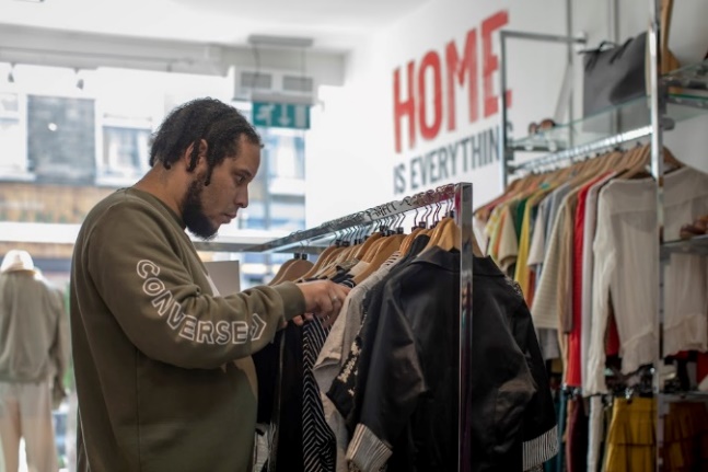 A person looking at clothes on a rackDescription automatically generated