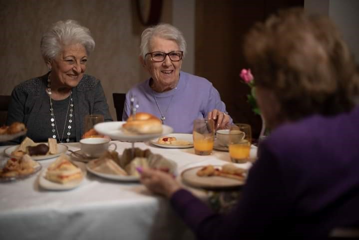 A group of people sitting at a table with foodDescription automatically generated with medium confidence