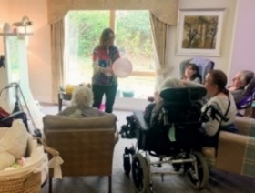 A person standing in a room with a group of peopleDescription automatically generated